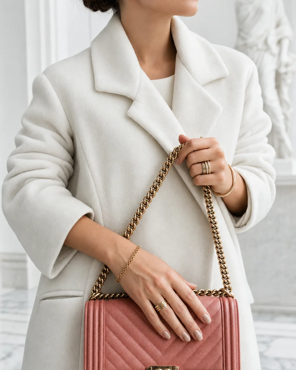 Manos con anillos de oro sobre una bolsa Chanel Boy rosa